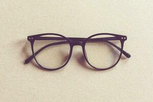 occhiali su beige cartone sfondo, minimalista piatto posare foto