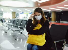 triste donna nel medico maschera aeroporto in attesa passeggeri foto