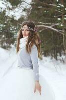 bellissimo sposa nel un' bianca vestito con un' mazzo nel un' innevato inverno foresta. ritratto di il sposa nel natura. foto