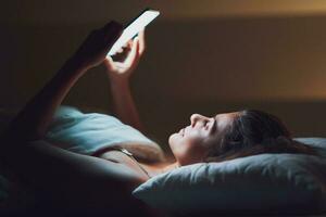 donna a notte nel letto con Telefono foto