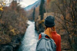 donna con zaino nel natura su il ponte vicino il fiume montagne avventura foto