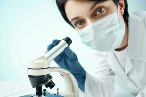 femmina medico nel medico maschera microscopio tecnologia ricerca foto