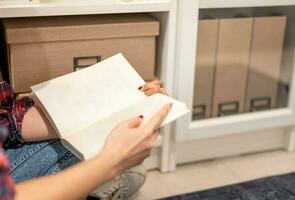 femmina mano Tenere taccuino e lettura libro con il spazio la zona per rilassante e il conoscenza mentre seduta su il divano nel pubblico biblioteca. foto