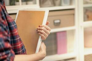 femmina mano Tenere un' vuoto spazio libro nel sua mano preparazione per organizzare nel il file cartella su il documento credenza a il ufficio. foto