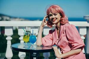 bella donna con rosa capelli nel un' cocktail ristorante all'aperto foto