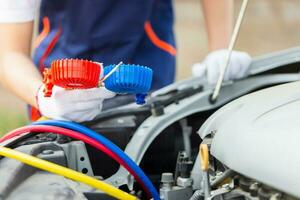 strumento di monitoraggio della tenuta del riparatore per controllare e riparare il sistema del condizionatore d'aria dell'auto, il tecnico controlla la ricarica del refrigerante del sistema di aria condizionata dell'auto, riparazione dell'aria condizionata foto