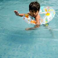 contento indiano ragazzo nuoto nel un' piscina, ragazzo indossare nuoto costume lungo con aria tubo durante caldo estate vacanze, bambini ragazzo nel grande nuoto piscina. foto