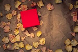 rosso regalo scatola con rosa fiore petali su spiegazzato kraft carta. piatto posizione. copia spazio su il scatola, per il marca. adatto per disposizione. vignettatura. foto