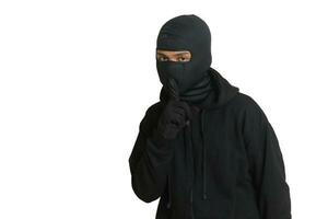 misterioso uomo indossare nero felpa con cappuccio in piedi e guardare a telecamera. isolato Immagine su grigio sfondo foto