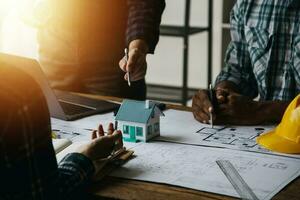 costruzione e struttura concetto di ingegnere o architetto incontro per progetto Lavorando con compagno e ingegneria utensili su modello edificio e planimetria nel Lavorando luogo, contrarre per tutti e due aziende. foto