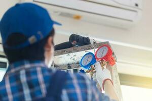 posteriore Visualizza di giovane riparatore fissaggio aria condizionatore unità, tecnico uomo installazione un aria condizionata nel un' cliente Casa, Manutenzione e riparazione concetti foto