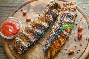 costolette di maiale alla griglia con pomodori sulla tavola di legno foto