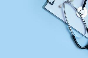 frammento di stetoscopio, tavoletta su blu sfondo con copia spazio. assistenza sanitaria e medicina concetto piatto posizione, superiore Visualizza foto