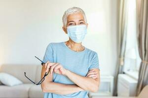 anziano donna nel respiratorio maschera. mascherato donna sembra a telecamera. freddo, influenza, virus, tonsillite, respiratorio patologia, quarantena, epidemico concetto. foto