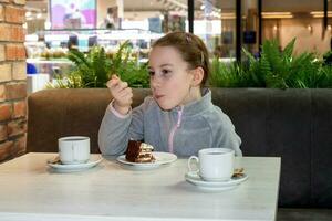 ragazza mangiare torta nel il cibo zona di il centro commerciale foto