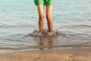 gamba di donna in esecuzione su spiaggia con acqua schizzi. estate vacanza. gambe di un' ragazza a piedi nel acqua su tramonto foto