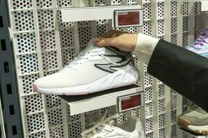 Da donna mani hold un' nuovo sneaker prese a partire dal il mensola di gli sport memorizzare foto