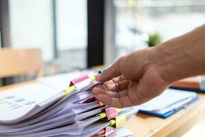 donna d'affari mani Lavorando su pile di carta documenti per ricerca e revisione documenti ammucchiati su tavolo prima invio loro per tavola di registi per uso corretta documenti nel incontro con uomo d'affari foto