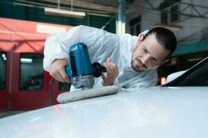 auto meccanico uso un elettrico lucidatrice per polacco il secco auto dipingere. dopo passaggio il dipingere a partire dal il auto pittura camera foto