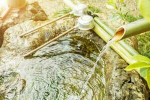 giapponese tradizionale su sfocato e sole bagliore sfondo. tsukubai è un' lavabo fornito a il Ingresso per santo posti per visitatori nel giapponese santuario o tempio. foto