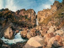 panoramico autunno paesaggio con verticale grande sultano cascata a montagna superiore nel luce del sole nel il jila-su tratto. cabardino-balcaria. Russia, Caucaso. alto caduta acqua nel settentrionale elbrus regione. foto