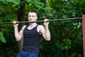 forte uomo fare pull-up su un' bar all'aperto foto