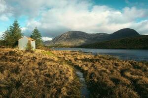 bellissimo paesaggio scenario con escursioni a piedi pista e Casa nel il natura con montagne nel il sfondo a derryclare naturale Riserva nel connemara nazionale parco, contea Galway, Irlanda foto