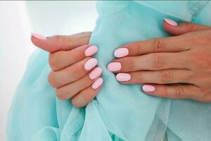 femmina mani con bellissimo di forma ovale chiodo, Opaco rosa manicure avvicinamento su un' blu sfondo. Gommalacca. copia spazio foto