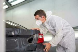 meccanico uomo pittura auto nel Camera, tecnico controllo il qualità di il la pittura, box auto pittura auto servizio riparazione e Manutenzione foto