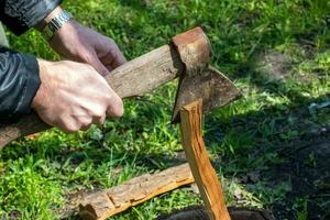 un' uomo è chopping legna per un' casa il camino. vacanza concetto nel il campagna foto