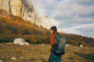 bella donna con un' zaino nel il autunno nel il montagne jeans cappello tempo libero rilassare foto