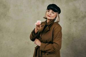 elegante anziano donna nel cappotto Tenere un' fiore moda foto