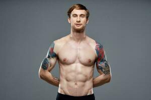 sportivo uomo con tatuaggi su il suo braccia pompato su stampa macho grigio sfondo foto