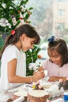 Due poco sorelle avendo divertimento mentre fabbricazione Natale Natività mestieri con a casa - vero famiglia foto