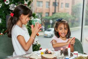 Due poco sorelle avendo divertimento mentre fabbricazione Natale Natività mestieri con a casa - vero famiglia foto