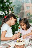 Due poco sorelle avendo divertimento mentre fabbricazione Natale Natività mestieri con a casa - vero famiglia foto