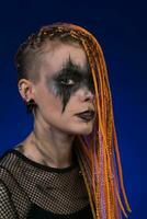 drammatico ritratto giovane donna con orrore nero palcoscenico trucco dipinto su viso, dreadlocks acconciatura foto