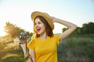 allegro donna con telecamera nel mani indossare cappello Aperto bocca natura fresco aria foto