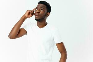 interessato giovane uomo di africano aspetto nel bianca maglietta tocchi il suo testa foto