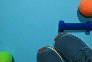blu manubrio, scarpe da ginnastica e arancia tennis palla indicando allenarsi Piano su blu sfondo. superiore Visualizza con copia spazio per qualunque design. salutare e fitness concetto foto