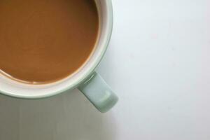 vicino su caldo cappuccino caffè nel un' blu tazza isolato su un' bianca sfondo foto