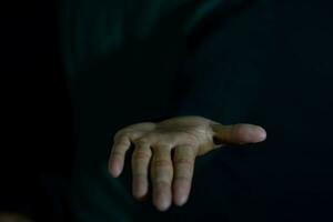 giovane uomo mostrando mani esso si intende di porzione mano su buio nero sfondo. selettivo messa a fuoco su dito foto