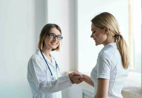 donna medico scuote mani con paziente nel bianca maglietta foto