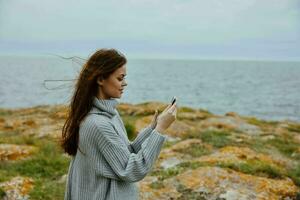 bella donna nel maglione con lungo capelli Telefono nel mano foto