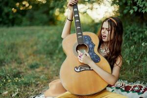 bellissimo donna giocando chitarra nel natura nel un' hippie estate Guarda, cantando canzoni stile di vita senza preoccupazioni foto