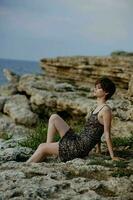 donna nel vestito seduta su il pietre paesaggio natura eleganza foto