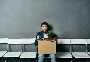 un' uomo con cose nel un' scatola si siede su un' sedia in attesa per malcontento foto