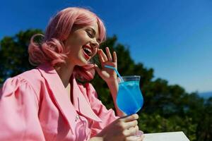 affascinante donna nel rosa vestito all'aperto con cocktail inalterato foto