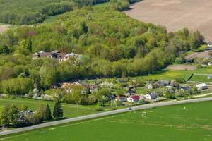 panoramico aereo Visualizza di eco villaggio con di legno case, ghiaia strada, giardini e frutteti foto