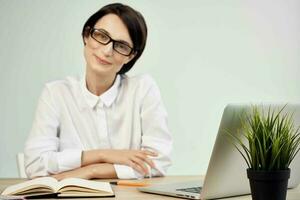femmina manager nel il ufficio con bicchieri fiducia in se stessi leggero sfondo foto